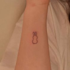 a small tattoo on the wrist of a woman with a bunny rabbit head in black ink