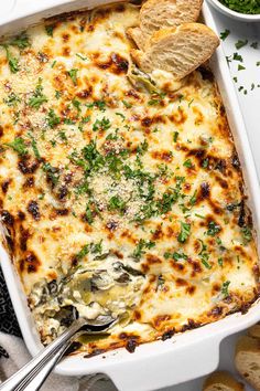 a casserole dish filled with spinach, cheese and parmesan bread