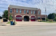 an old fire station with two red doors on it's front and side entrance