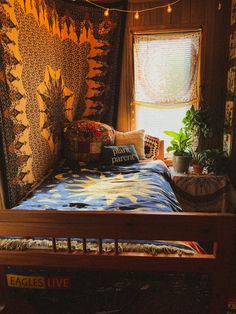 a bed in a room with a quilt on the wall and potted plants next to it