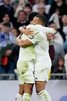 two soccer players hugging each other on the field