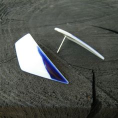 a pair of white and blue earrings sitting on top of a piece of tree trunk