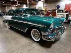 an old green and white car parked in a garage