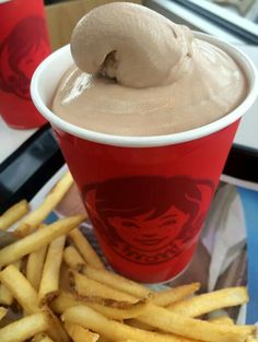 a red cup filled with ice cream next to french fries