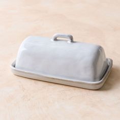 a white ceramic covered dish sitting on top of a table