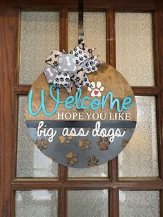 a welcome sign hanging on the front door of a dog's house with paw prints