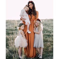 two women and three girls are standing in the grass with their arms around each other