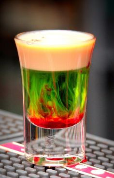 a shot glass filled with liquid sitting on top of a computer mouse pad in front of a keyboard