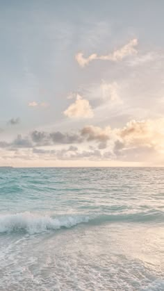 the sun is setting over the ocean with waves crashing on the shore and clouds in the sky