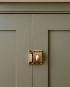 a close up of a door handle on a green cabinet with brass handles and knobs