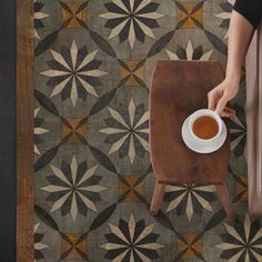 a person sitting at a table with a cup of coffee in front of them on the floor