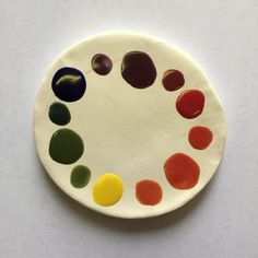 a white plate with several different colored circles on the front and side, all painted in various colors