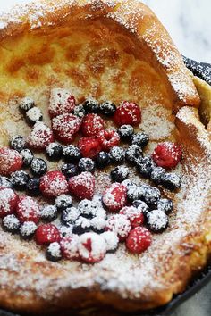 a pancake with berries and powdered sugar on top