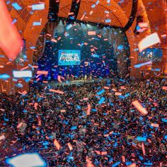 confetti is thrown in the air at a convention or conference hall as people look on