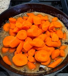 a pan filled with lots of cut up carrots on top of a gas stove