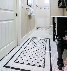 a white bathroom with black and white tile flooring