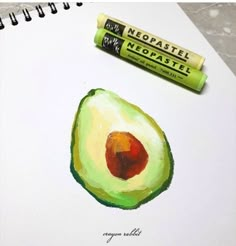 an avocado is next to a tube of lip balm on top of a notebook