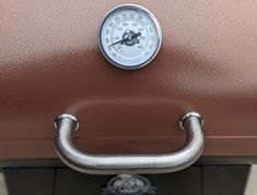 a thermometer mounted on top of a brown suitcase