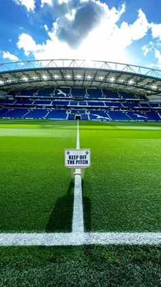 an empty soccer field in front of a stadium with bright lights on the sidelines