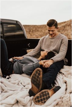 two people sitting in the bed of a pickup truck