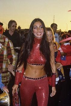 a woman in red and silver outfit standing next to other people