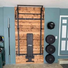 a gym room with a wall mounted squat machine and barbells on the wall