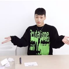 a young man sitting at a table with his hands out in front of the camera