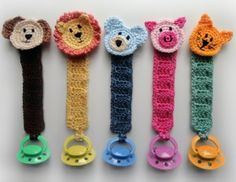 five crocheted animal key fobs in different colors and sizes are lined up on a white surface