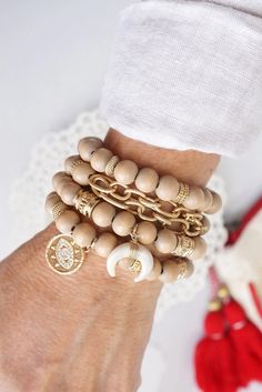 a woman's hand with several bracelets on her wrist and two gold charms