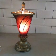 a red lamp sitting on top of a table next to a white brick wall in a room