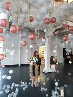 a woman is standing in front of balloons and streamers that are floating from the ceiling