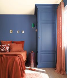 a bedroom with blue walls and orange bedding