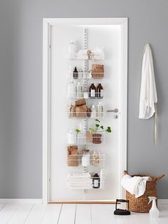 a white door with baskets and towels hanging on the wall next to an open closet