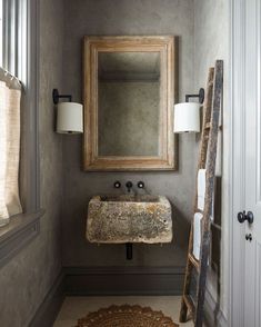 a bathroom sink sitting under a mirror next to a ladder