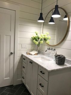 a bathroom with two sinks and a large round mirror