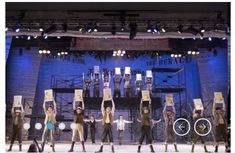 a group of people standing on top of a stage holding cardboard boxes over their heads