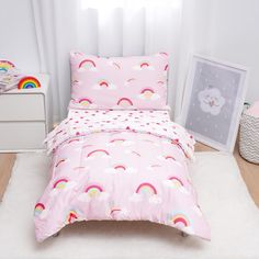 a child's bedroom with pink bedding and rainbows