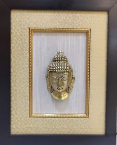 a golden buddha head in a gold frame on a white and black wall with an ornate pattern