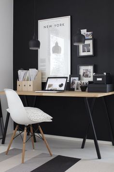 a black and white office with a desk, chair and pictures hanging on the wall