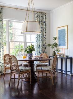 a dining room table with four chairs and a lamp hanging from it's ceiling