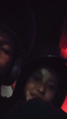 two people sitting in the back of a car at night, one person wearing headphones