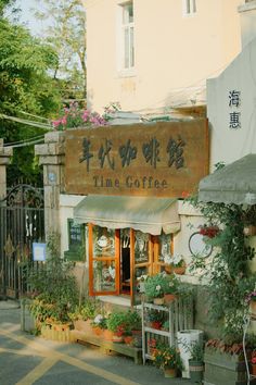 an outside view of a coffee shop with potted plants on the front and in chinese writing