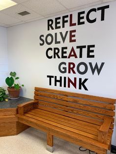 a wooden bench sitting in front of a wall that says reflect solve create grow think