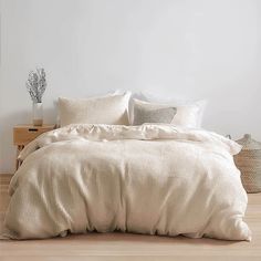 a bed with white sheets and pillows on top of wooden floor next to nightstands