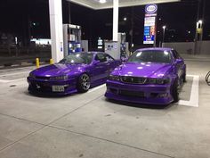 two purple cars parked next to each other at a gas station