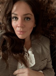 a woman with long hair wearing a blazer and white shirt posing for the camera