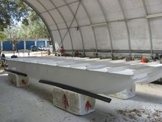 a white boat sitting inside of a building under a roof with no people around it