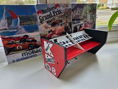 a red and black table top with two racing cars on it next to some posters