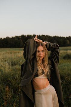 a woman standing in a field with her hands on her head