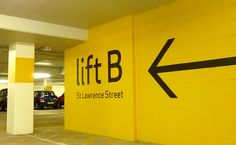 a parking garage filled with lots of parked cars next to a yellow sign that says lift b